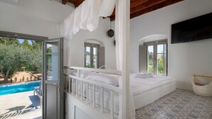Una camera da letto con un'ampia finestra, un letto, una televisione e vista su una piscina.
