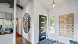 A modern interior with a circular mirror, a black door, and a textured wall hanging. - Mid-century home with panoramic views and hot tub! (Maggie Valley)