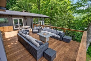 A deck with outdoor furniture, including a sofa and chairs, and a fire pit.