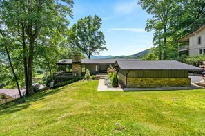 A modern house with a stone exterior, a covered porch, and a well-maintained lawn.