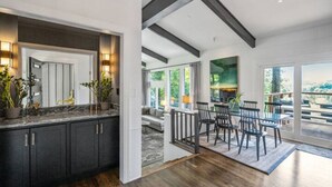 A modern kitchen with dark cabinetry and a marble countertop, leading to a dining area with a table and chairs. - Mid-century home with panoramic views and hot tub! (Maggie Valley)