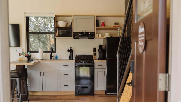 A compact kitchen with a stove, microwave, and refrigerator. - Lynx Cabin @ Keystone Kozy (Soldotna)