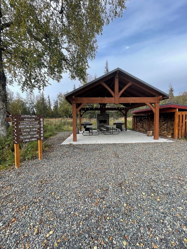 Guests can enjoy a cozy gathering spot with a stone fireplace and picnic tables.