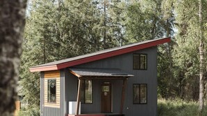 A small, single-story cabin with a sloped roof, a front porch, and a set of steps leading to the entrance. - Lynx Cabin @ Keystone Kozy (Soldotna)