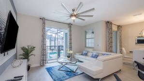 Un salon moderne avec un canapé blanc, une table basse en verre et un ventilateur de plafond.