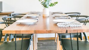 A dining area with a wooden table, black chairs, a potted plant, and a large wooden wall art piece.