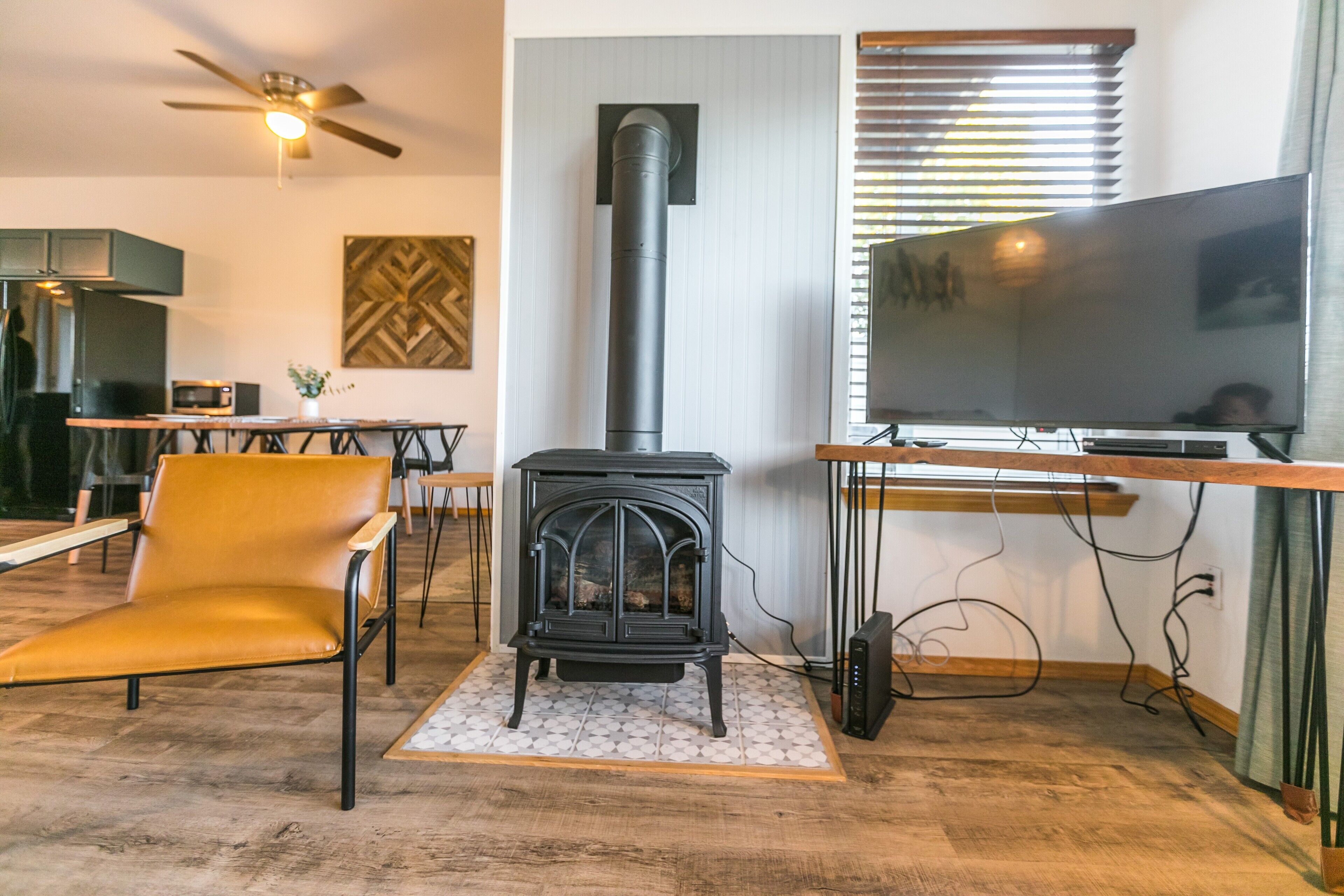 A cozy living room with a black wood-burning stove, a flat-screen TV, and a comfortable yellow chair.
