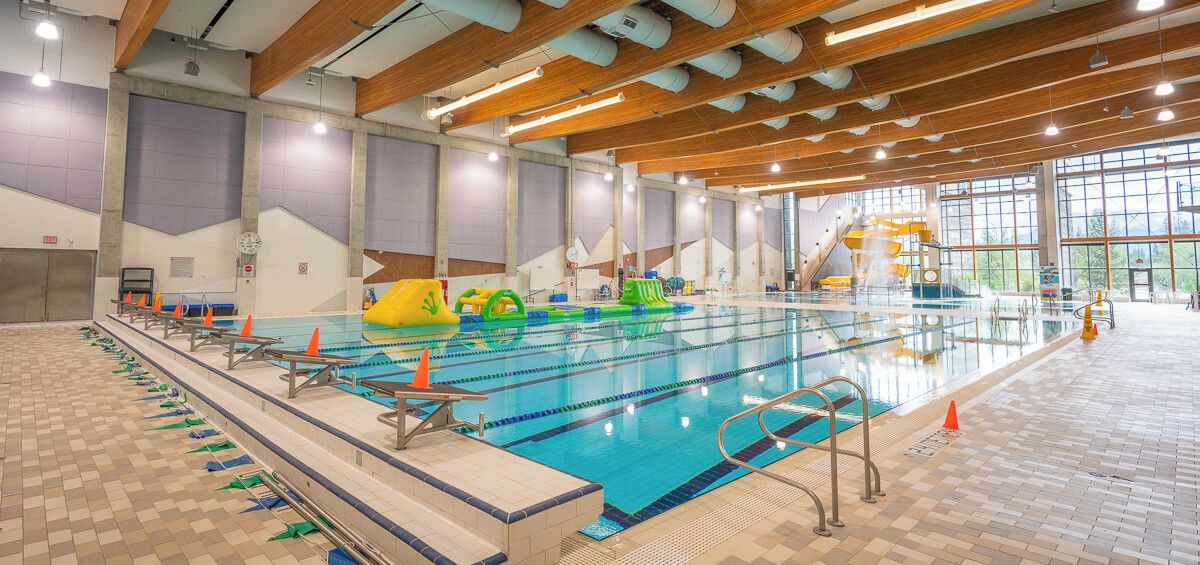 En indendørs swimmingpool med baner, startbloker og et springtårn.