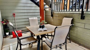 Eine kleine Terrasse mit Tisch, Stühlen, einem Blumentopf und einem roten Sessel.
