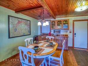 Un área de comedor con una mesa y sillas de madera, un mapa en la pared y una cocina con armarios de madera y una ventana.