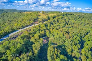 An aerial view of a forested area with a road, a bridge, and a house. - Best View! Beautiful Ozarks cabin ON rim of AR Grand Canyon! Many new updates (Jasper)