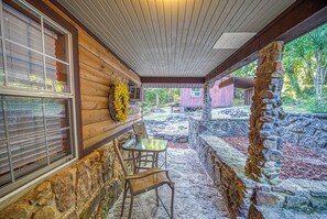 Un patio cubierto con paredes de piedra, vigas de madera y un pilar de piedra.