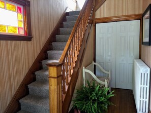 Un escalier avec des rampes en bois et des marches recouvertes de moquette, menant à une porte blanche.