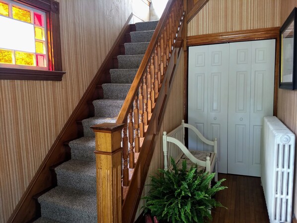 A staircase with wooden railings and carpeted steps leading to a white door.