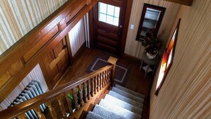A wooden staircase with a handrail, a door with a window, and a small rug on the landing. - White Mountains Victorian on Main Street (Gorham)