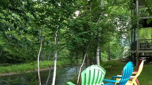 A riverside setting with a wooden deck and colorful plastic chairs. - White Mountains Victorian on Main Street (Gorham)