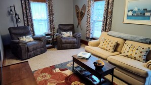 A living room with two armchairs, a sofa, a coffee table, and a patterned rug. - White Mountains Victorian on Main Street (Gorham)