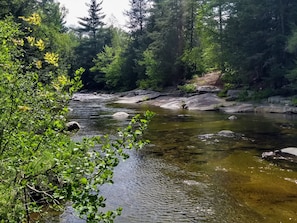 Une rivière qui traverse une zone boisée, avec des rochers et de la végétation.