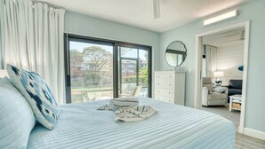 Une chambre avec un grand lit, une commode, un miroir et une vue sur l’extérieur.