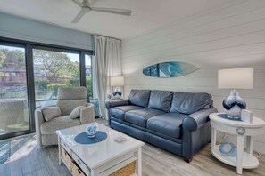 A modern living room with a leather sofa, a white coffee table, and a ceiling fan. - Beautiful Park Shore Resort Condo Unit 113 (Naples)