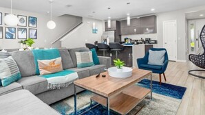 A modern living room with a sofa, coffee table, and a blue rug. - Disney Getaway w/ Splash Pool + Kids’ Theme Rooms (Kissimmee)