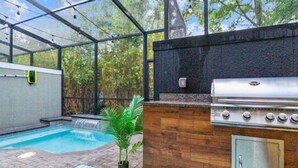 An outdoor kitchen area with a grill, a small pool, and a wooden deck. - Disney Getaway w/ Splash Pool + Kids’ Theme Rooms (Kissimmee)
