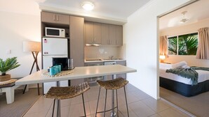 Eine kleine Küche mit Mikrowelle, Kühlschrank und Barhocker.