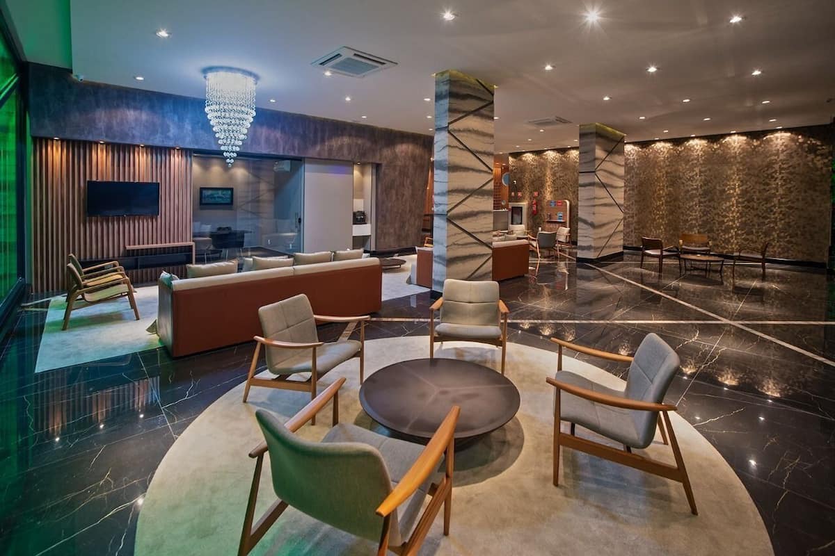 A modern lobby with a reception desk, seating area, and a large chandelier.