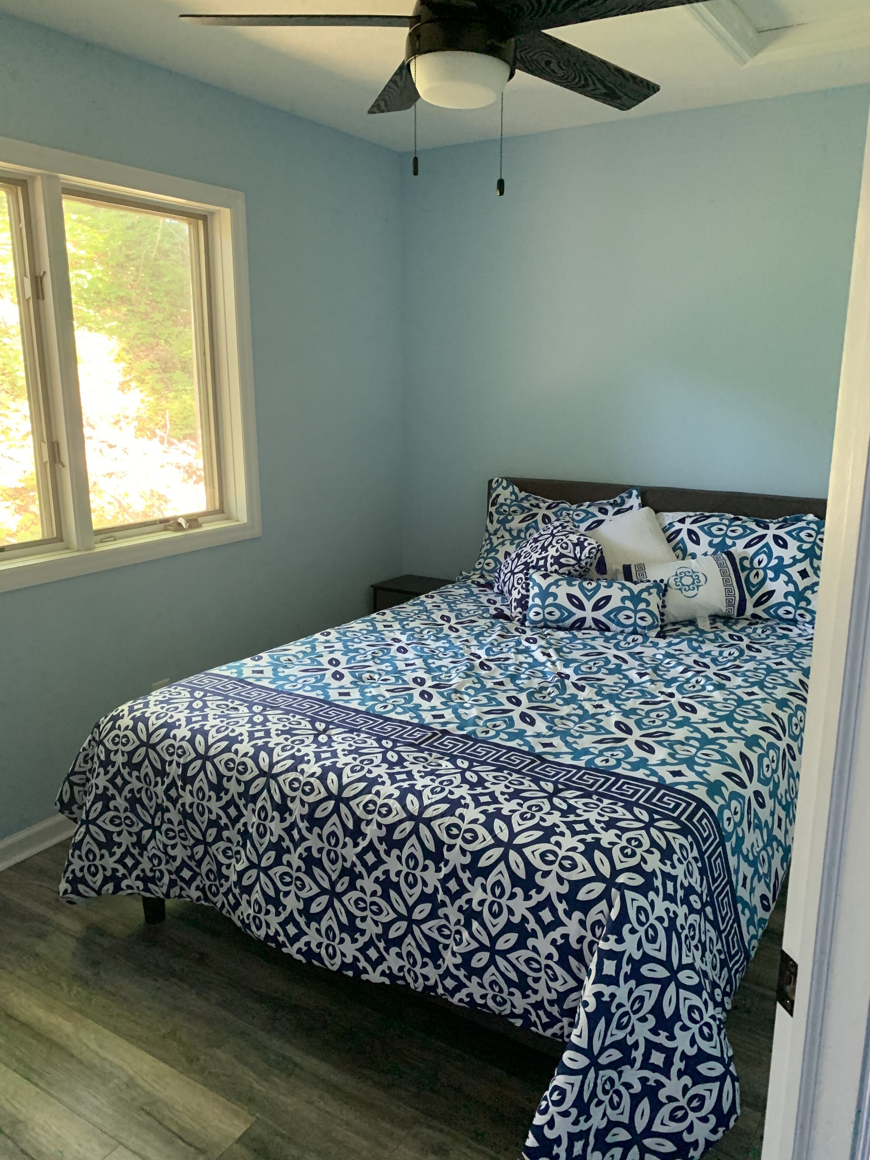 A bedroom with a bed, a ceiling fan, and a window.