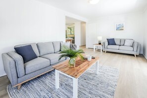 A modern living room with a grey sofa, a wooden coffee table, and a patterned rug. - High On Jeffery in the Heart of Agnes Water (Agnes Water)