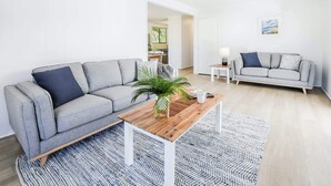 A modern living room with a grey sofa, a wooden coffee table, and a patterned rug. - High On Jeffery in the Heart of Agnes Water (Agnes Water)