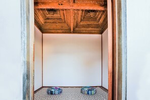 A narrow hallway with patterned floor tiles and a wooden ceiling with intricate carvings. Two round, colorful objects are placed on the floor. - High On Jeffery in the Heart of Agnes Water (Agnes Water)