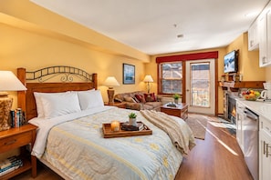 A hotel room with a bed, a sofa, a dining area, and a fireplace.