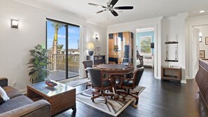 A spacious living area with a large round table, comfortable seating, a ceiling fan, and a view through a sliding glass door. - Pristine Waterfront Villa in Cape Coral with Lagoon Style Pool Spa and Boat Lift (Cape Coral)