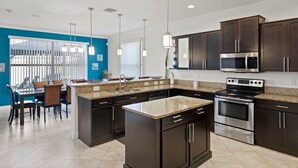 A modern kitchen with dark cabinets, stainless steel appliances, and a central island. - Pristine Waterfront Villa in Cape Coral with Lagoon Style Pool Spa and Boat Lift (Cape Coral)