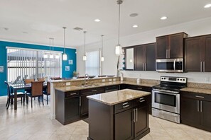 Una cocina moderna con armarios oscuros, electrodomésticos de acero inoxidable y una isla central.
