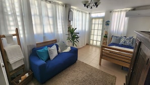 Une pièce chaleureuse avec un canapé bleu, un lit en bois, une petite table et une plante en pot.