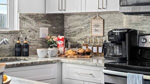 A modern kitchen with white cabinets, a marble countertop, a coffee maker, and a sign that reads "coffee bar". - Pet-Friendly Home with a Hot Tub, Climbing Wall, King Bed & Gym by Mane Suites! (Tampa)