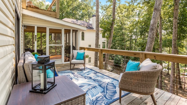 A wooden deck with wicker furniture, a patterned rug, and a lantern. - Private In the woods cabin With a Lakeview (Dawsonville)