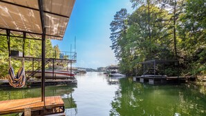 A calm river with boats docked on the left, a wooden dock on the right, and a covered area in the foreground. - Private In the woods cabin With a Lakeview (Dawsonville)