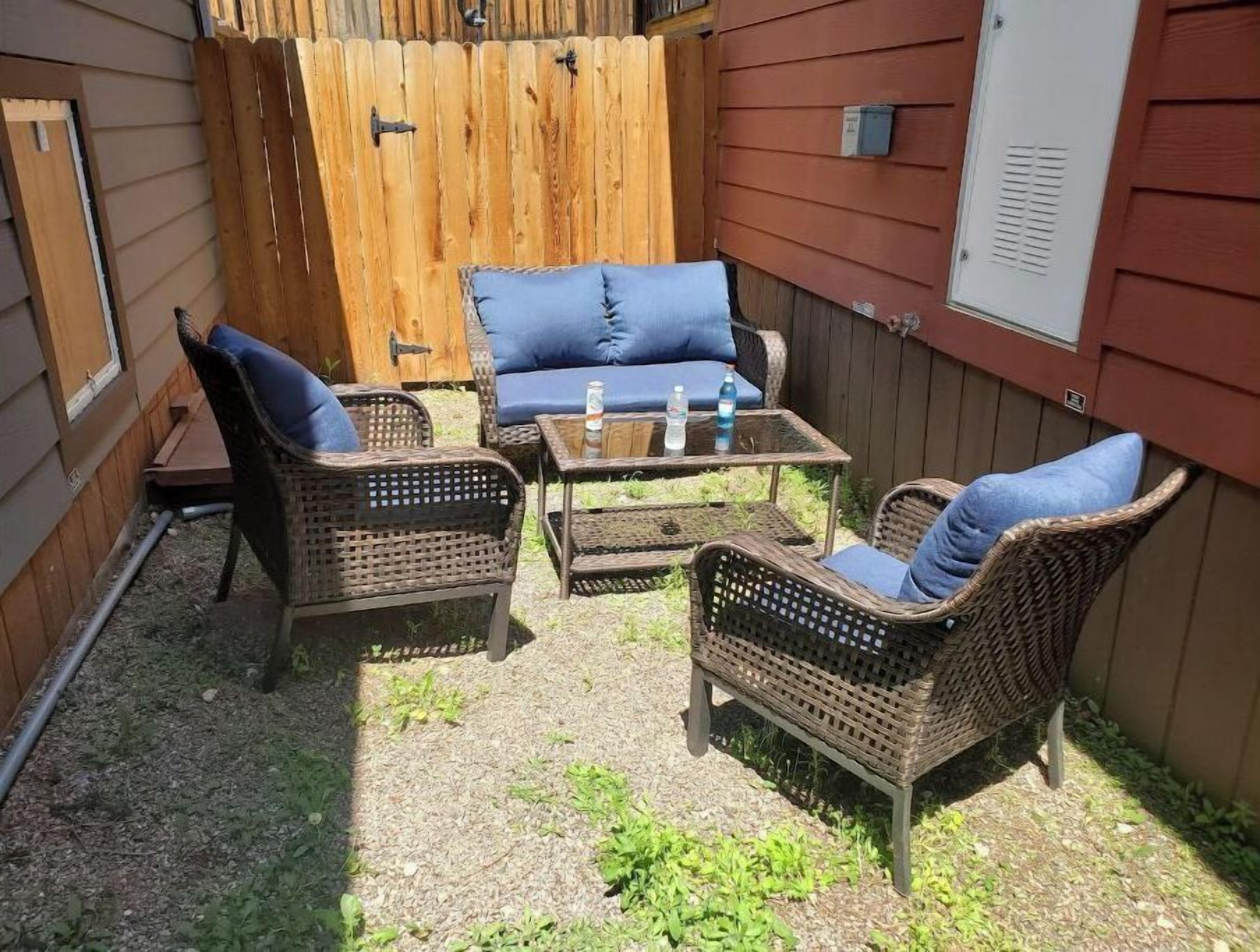 Eine Terrasse mit Korbmöbeln, einem Tisch und einem blauen Kissen.
