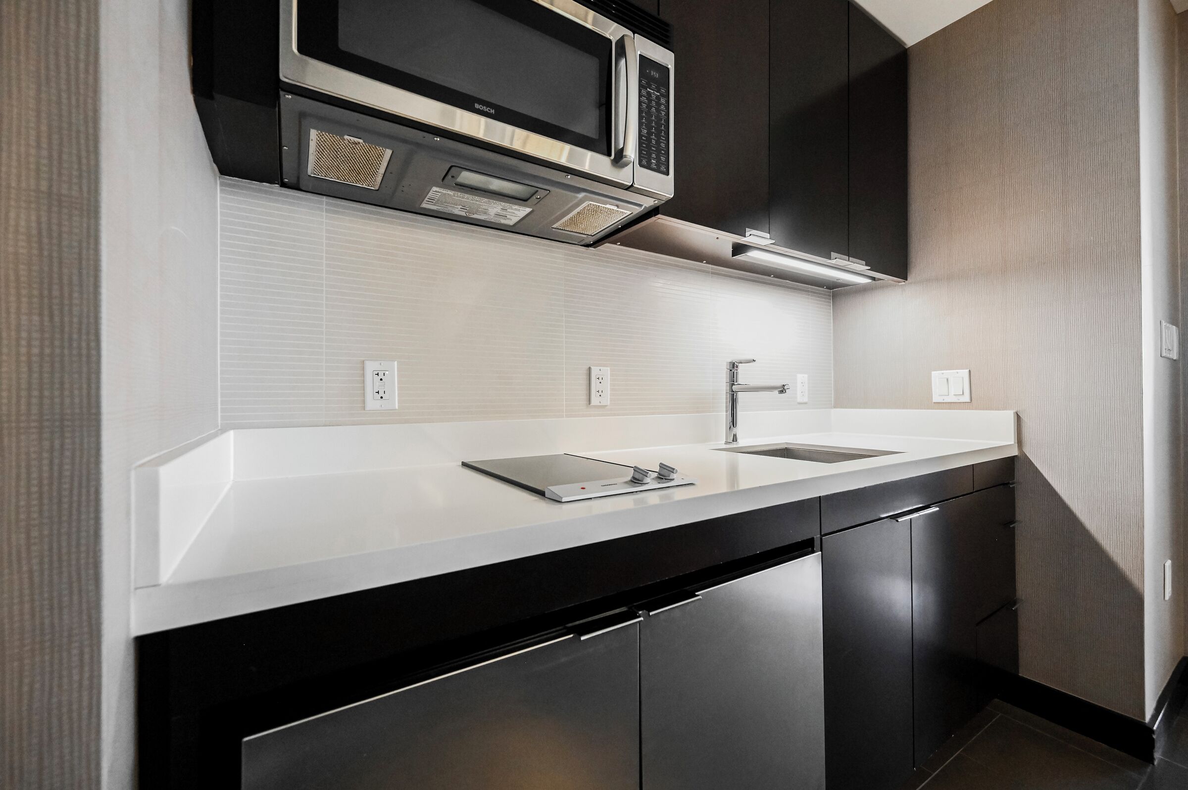 A modern kitchen with a Bosch microwave, a built-in oven, and a stainless steel dishwasher.