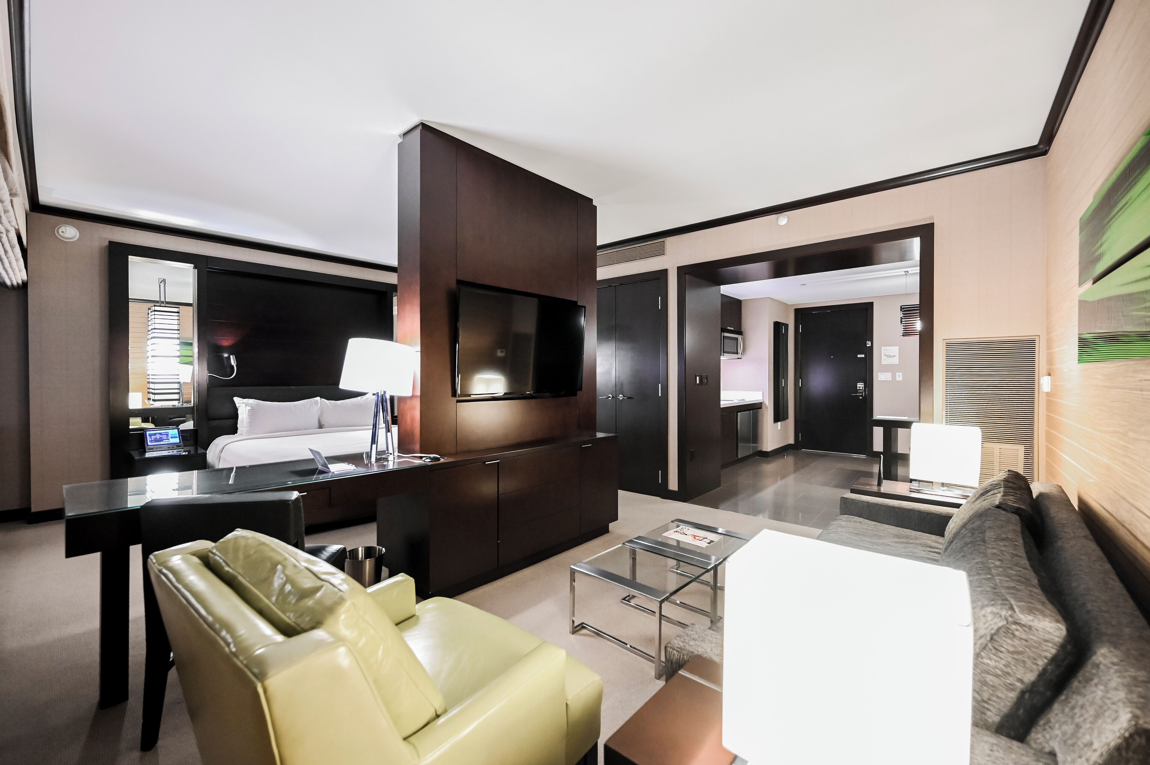 Ein modernes Hotelzimmer mit Bett, Schreibtisch, Sessel, Sofa und Fernseher.