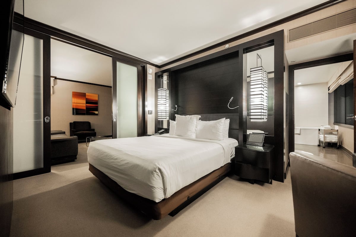Ett modernt hotellrum med en stor säng, ett skrivbord med en bärbar dator och en garderob.