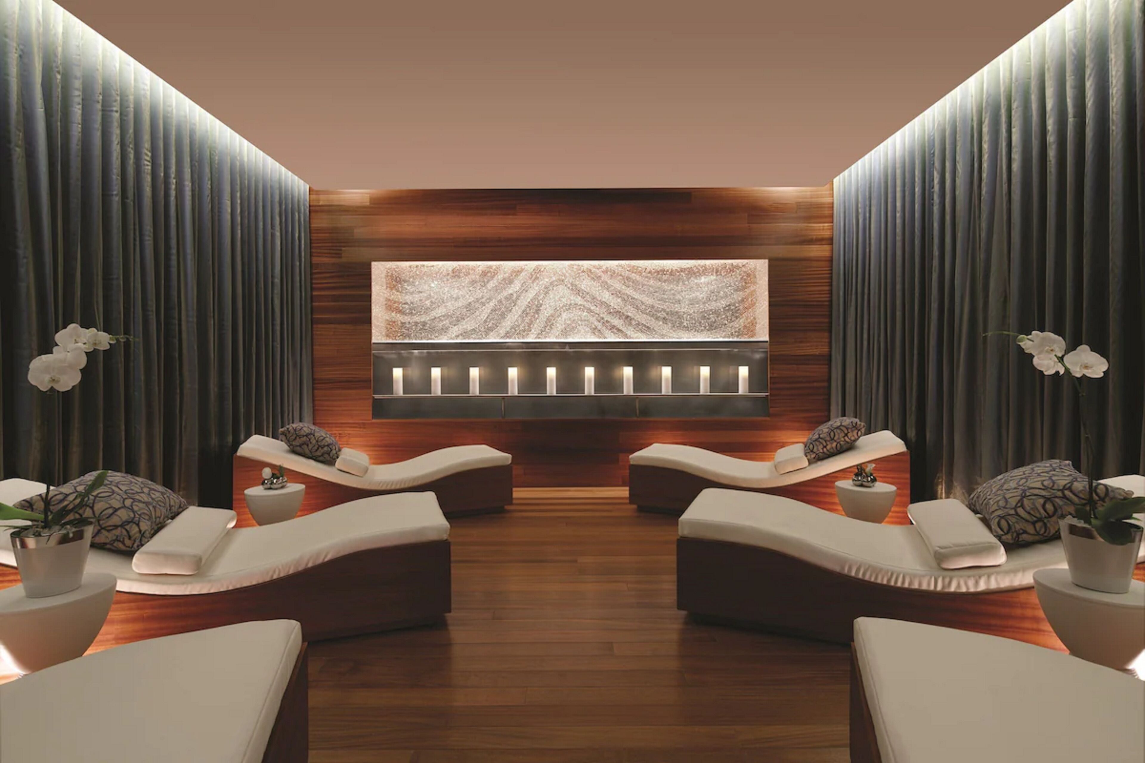 Een wellnessruimte met twee comfortstoelen, een massagebank en een groot decoratief paneel.