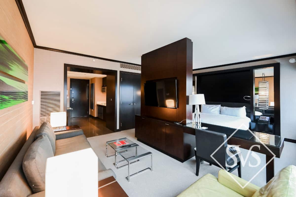 Ett modernt hotellrum med en stor säng, ett skrivbord, en soffa och en TV.