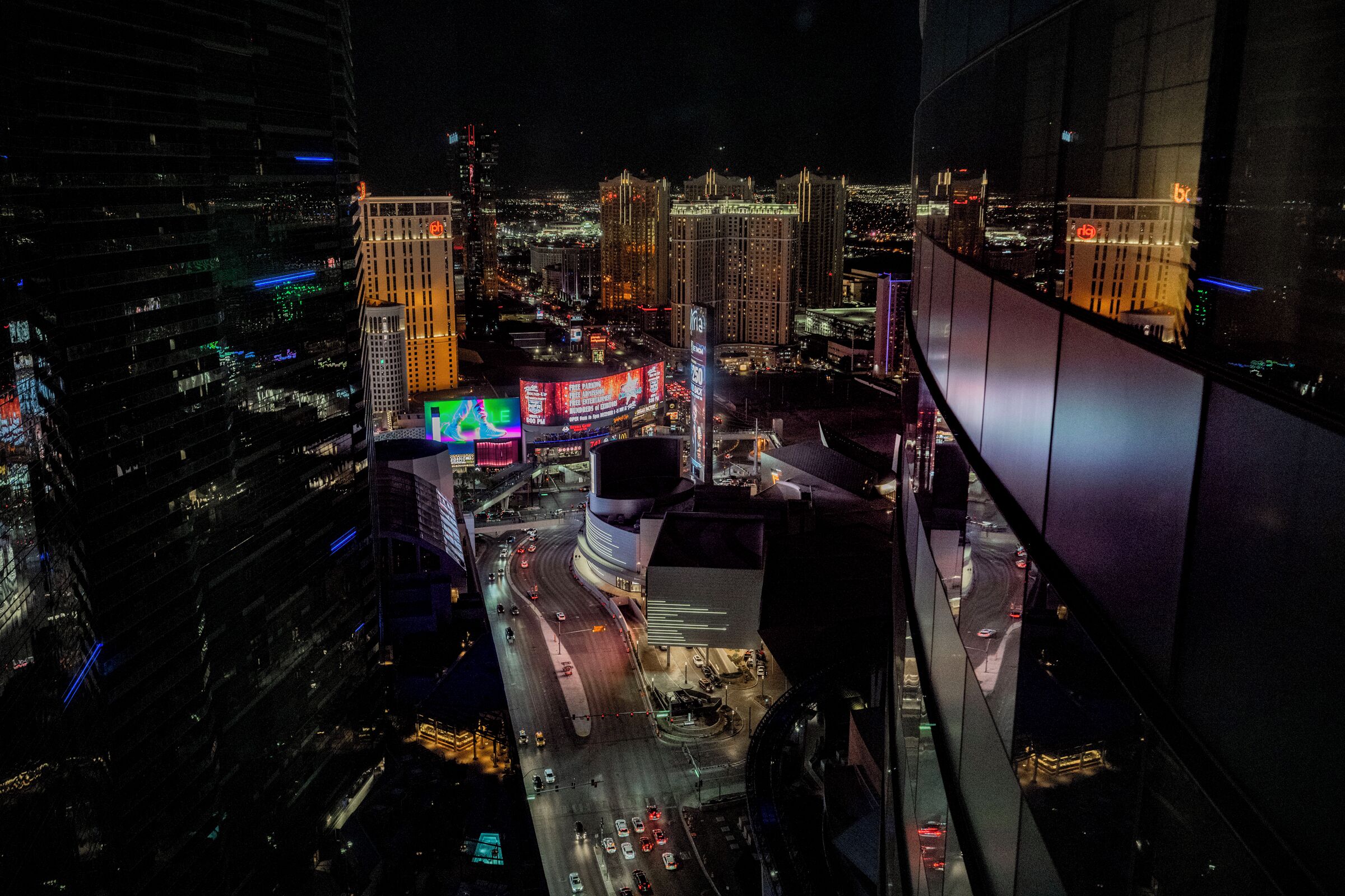 A nighttime cityscape with illuminated buildings and a busy intersection.