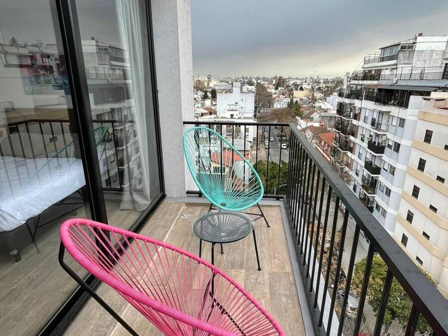 Un balcón con dos sillas, una cama y vistas de la ciudad.