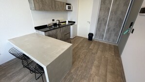 Eine kleine Küche mit Mikrowelle, Spüle und einem kleinen Mülleimer.