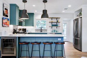 Een moderne keuken met turquoise kastjes, een roestvrijstalen koelkast en een bar met krukken.